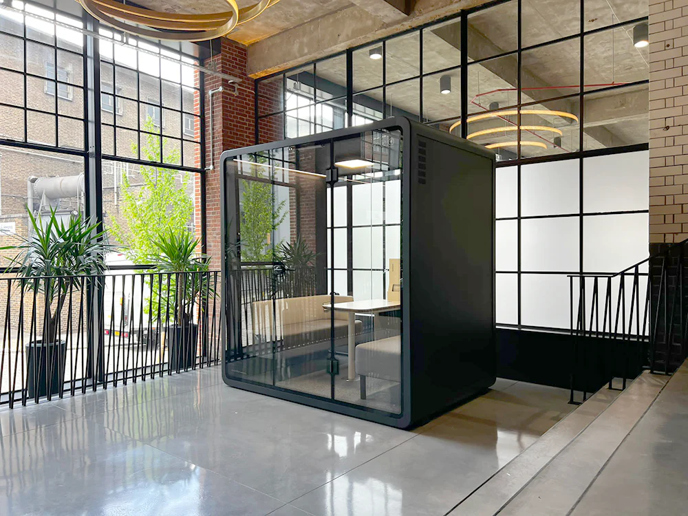 Salle de réunion QUATTRO pour quatre personnes avec deux canapés et table centrale, bureau moderne avec cabines acoustiques