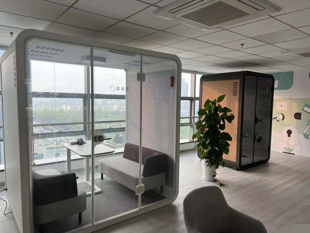 Salle de réunion pour quatre personnes avec une cabine acoustique individuelle devant une paroi vitrée dans un bureau moderne